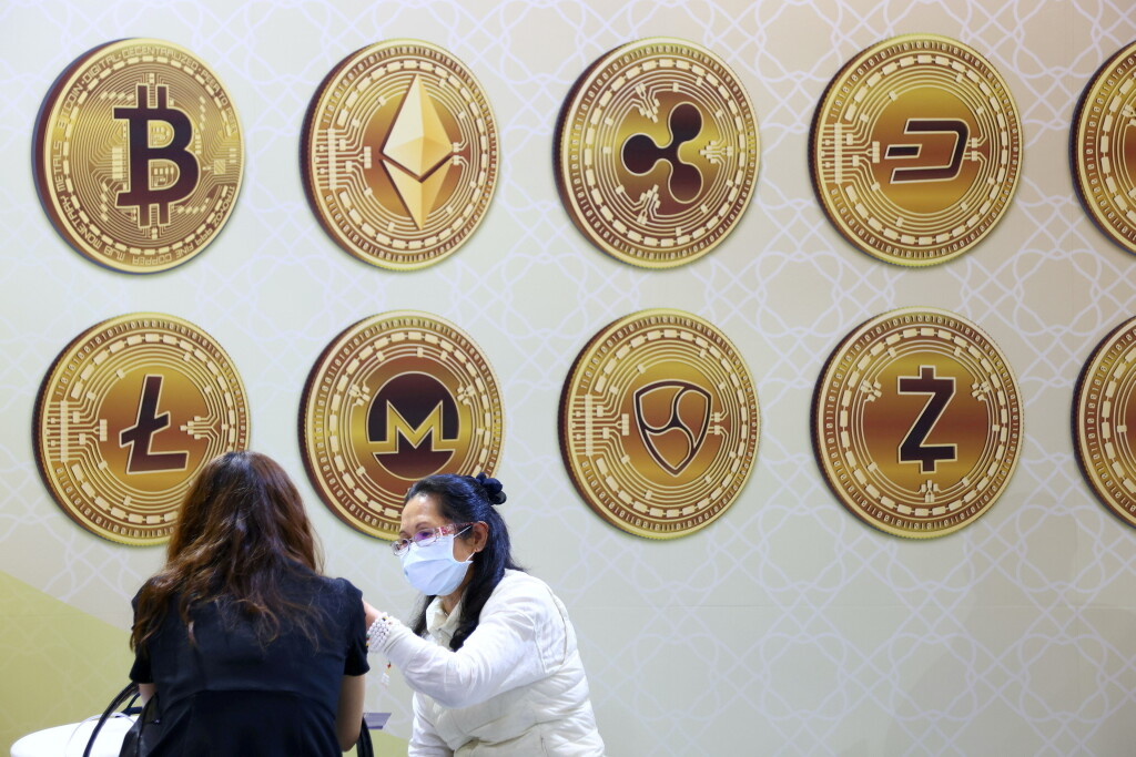 FILE PHOTO: Customers talk against a backboard with signs of cryptocurrency during 2020 Taipei International Finance Expo in Taipei, DOCU_GRUPO
